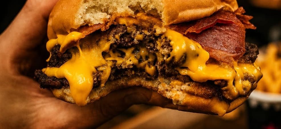 Mordida a una hamburguesa doble cheddar con bacon